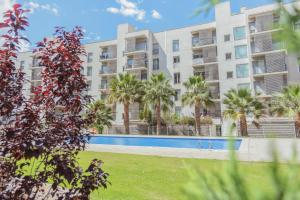 an apartment building with a swimming pool and palm trees at Clauhomes Suite de Mozart in Tarragona
