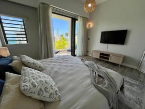 a bedroom with a bed with pillows and a television at Summer beachfront apartment in Belle Mare