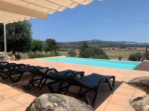 um grupo de cadeiras sentadas ao lado de uma piscina em Almojanda 3 olive tree em Fortios