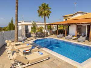 a swimming pool with lounge chairs next to a house at Villa Socrates in Protaras
