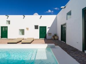 a swimming pool in front of a white building at Casa Montelongo - Adults Only in La Oliva