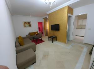 a living room with a couch and a tv at Ennasr 2 - Rez-de-Chaussée Chaleureux - Internet Fibre - Chaines International - Commerces et Services à Proximité - Service Navette in Ariana
