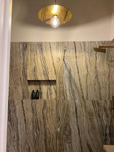 La salle de bains est pourvue d'un mur en marbre et d'un éclairage. dans l'établissement Rosina Apartament il corso, à Torre del Greco