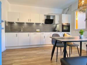 a kitchen with white cabinets and a table with chairs at Ferienwohnung Seesprung am Bodensee in Gaienhofen