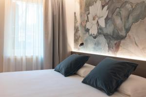 a bedroom with a bed with two pillows and a painting at Locanda Alla Porchetta in Negrar +9 photos