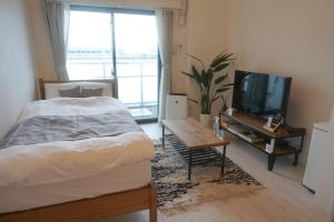 Schlafzimmer mit einem Bett, einem TV und einem Tisch in der Unterkunft REVISION Kairouyama-tei - Vacation STAY 15802 in Hiroshima