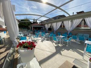 un patio con sedie blu, tavoli e ombrelloni bianchi di Angelina Hotel a Ormos Panagias