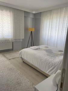 sypialnia z łóżkiem z białą pościelą i zasłonami w obiekcie Yeşil ve huzur dolu bir daire w mieście Bulancak