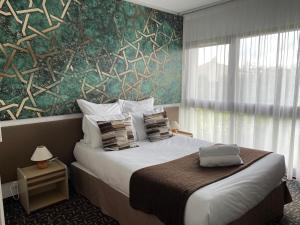1 dormitorio con 1 cama grande y pared verde en Hôtel-Restaurant La Belle Poule - Contact Hotel, en Rochefort