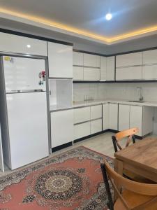 - une cuisine avec des placards blancs, une table et un réfrigérateur dans l'établissement Yeşil ve huzur dolu bir daire, à Bulancak