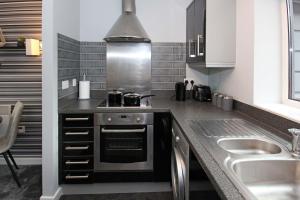 a kitchen with a stove and a sink at Broad Gauge Apartments in Wolverhampton