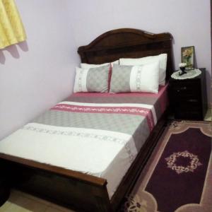 łóżko z drewnianym zagłówkiem w pokoju w obiekcie شقة بجنب مطار المسيرة 