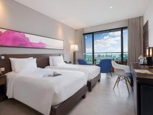 a hotel room with two beds and a desk at Novotel Phu Quoc Resort in Phu Quoc