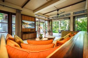 un salon avec des coussins orange et un canapé dans l'établissement The Ubāri Bali - Luxury Riverside Escape, à Ubud