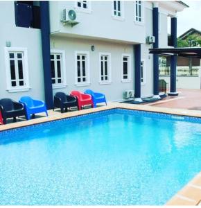 a swimming pool with blue and red chairs next to a building at BTT Homes in Lekki