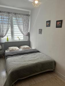a bed in a bedroom with a window and a bedspread at Dworcowa przy basenie in Olsztyn