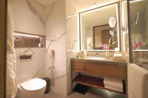 a bathroom with a sink and a toilet and a mirror at Taj Bangalore in Devanahalli-Bangalore