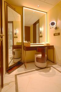a bathroom with a toilet and a large mirror at Taj Bangalore in Devanahalli-Bangalore