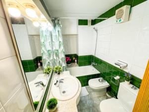 a green and white bathroom with a toilet and a sink at Cisne del Mar ComoTuCasa in Castellón de la Plana