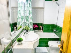 a green and white bathroom with a sink and a tub at Cisne del Mar ComoTuCasa in Castellón de la Plana