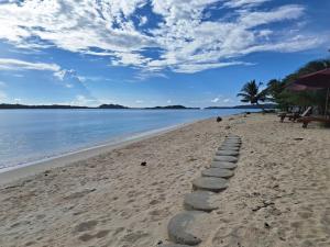 a beach with a row of rocks in the sand w obiekcie Jelita Beach Mentawai w mieście Tua Pejat