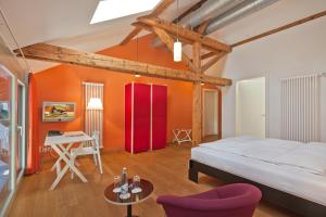 una camera da letto con pareti arancioni, un letto e un tavolo di Boutique-Hotel Auberge Langenthal a Langenthal