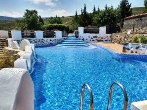 a swimming pool with blue water and white chairs at Moli Colomer in La Torre d'En Besora