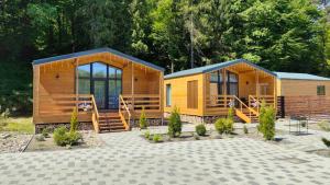two large wooden lodges with trees in the background at OLENEVO Park Houses in Olenʼovo