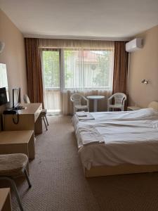 a hotel room with a bed and a desk and a window at Relax Sarafovo in Burgas