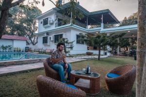 a man sitting in a chair in front of a house at Wildwood Retreat - Awas Beach in Avas