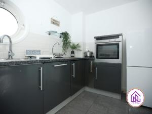 uma cozinha com armários pretos, um lavatório e um micro-ondas em Victoria Wharf, Stunning Cardiff Bay Apartment em Cardiff