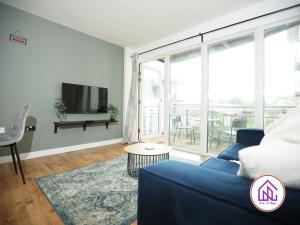 uma sala de estar com um sofá azul e uma grande janela em Victoria Wharf, Stunning Cardiff Bay Apartment em Cardiff