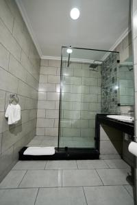 a bathroom with a glass shower with a sink at Hotel Bab Mansour in Meknès
