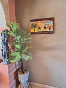 een palmboom in een vaas naast een schilderij bij Riad Merzouga Dunes in Merzouga
