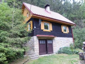 una pequeña casa con una puerta marrón en un bosque en Chata U skřítka en Valašská Bystřice