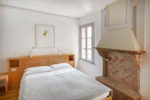 a white bedroom with a bed and a fireplace at Locanda Osteria La Fefa in Finale Emilia