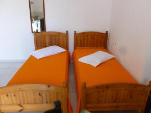 2 camas en una habitación con naranja en Akrogiali Rooms & Studios, en Drymonas