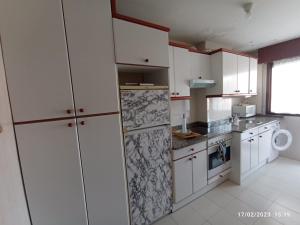 uma cozinha com armários brancos e um frigorífico em Piscina comunitaria y parking en Mogro em Mogro