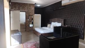 a bedroom with a bed and a brick wall at Naldorado Executive Villa in Nelspruit