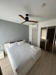 1 dormitorio con 1 cama blanca y ventilador de techo en Cassia apartment en Laguna Phuket