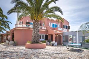 a palm tree in front of a pink house at Villa Paradis - Quartos in Pêra