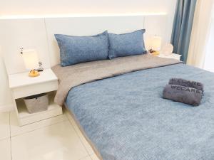 um quarto com uma cama com um cobertor azul e almofadas em The Popoli Icon City Petaling Jaya em Kampong Baharu Sungai Way