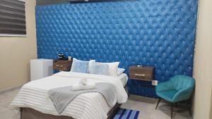 a bedroom with a blue padded wall with a bed and a blue chair at Naldorado Executive Villa in Nelspruit