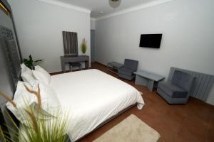 a bedroom with a bed and two chairs and a television at Hotel Bab Mansour in Meknès