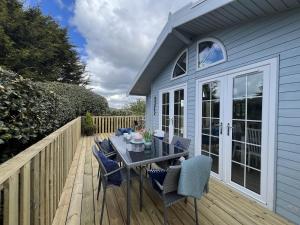a patio with a table and chairs on a deck at Holly Blue - Cosy wooden lodge Kippford in Dalbeattie