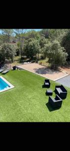 a green yard with a swimming pool and some benches at Villa Coco avec jardin piscine et terrain de boules de 180 m carrés in Les Arcs sur Argens