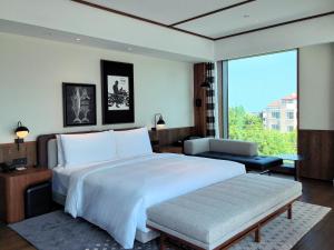 a bedroom with a large bed and a large window at Flow and Co. Qingdao, Autograph Collection in Qingdao