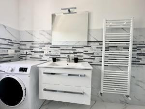 a white bathroom with a sink and a washing machine at casa la Rosa in Lesa
