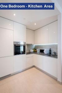 a one bedroom kitchen area with white cabinets at Bentley Holiday Apartments - West One in Gibraltar