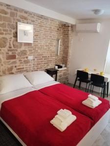 1 dormitorio con 1 cama grande de color rojo y pared de ladrillo en Studio Apartment Ana, en Zadar